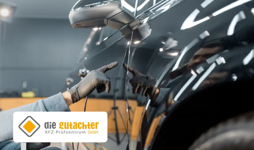Eine Person mit schwarzen Handschuhen prüft die Seite eines glänzenden schwarzen Autos auf Schäden. Das Logo "die gutachter KFZ-Prüfzentrum GmbH" und die Expertise von KFZ Gutachter Dresden sind in der unteren linken Ecke zu sehen.