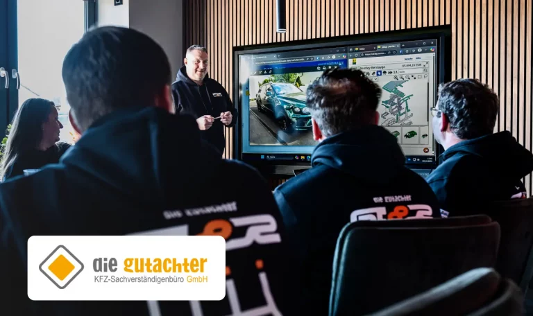 Eine Gruppe von Personen in die Gutachter GT8R Kapuzenpullovern ber&auml;t sich zu einem Haftpflichtgutachten &uuml;ber ein hochpreisiges Auto. Auf dem Bildschirm werden Bilder des Fahrzeugs sowie eine Explosionszeichnung betroffener Teile gezeigt. Das Logo "die gutachter" und der Schriftzug "KFZ Sachverst&auml;ndigenb&uuml;ro&rdquo; erscheinen in der unteren linken Ecke.